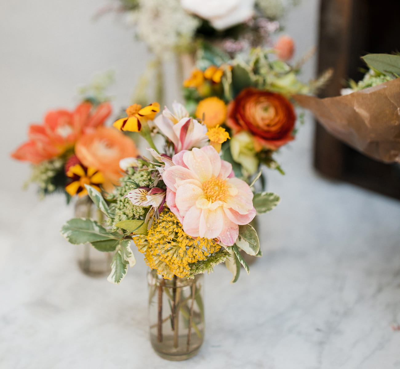 Several small glass vases on the white countertop hold cute little DIY flower bouquets.